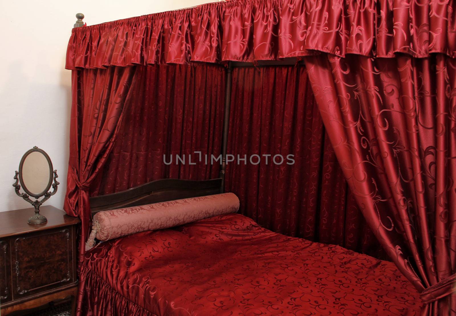 Red upholstered early century canopy bed.