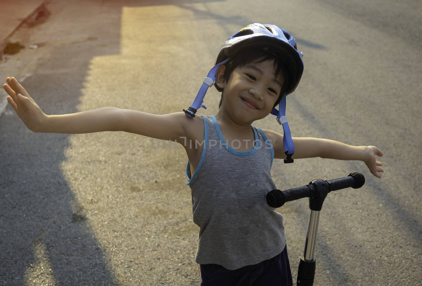 A 4-year-old Asian boy smiled happily with the opportunity to exercise by riding a scooter in the evening during the coronavirus crisis.