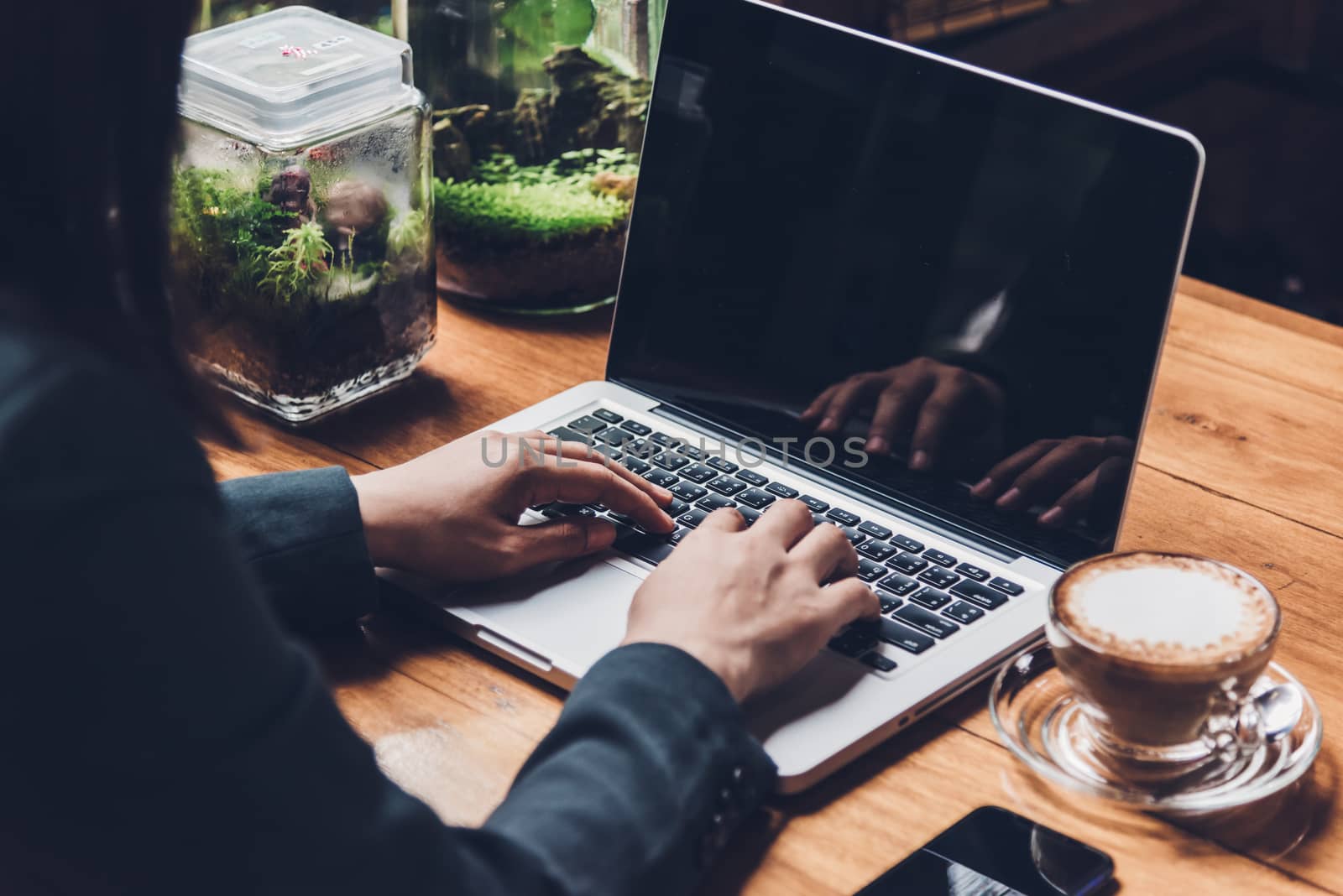 Young businesswoman is working by typing on his computer laptop in a coffee shop