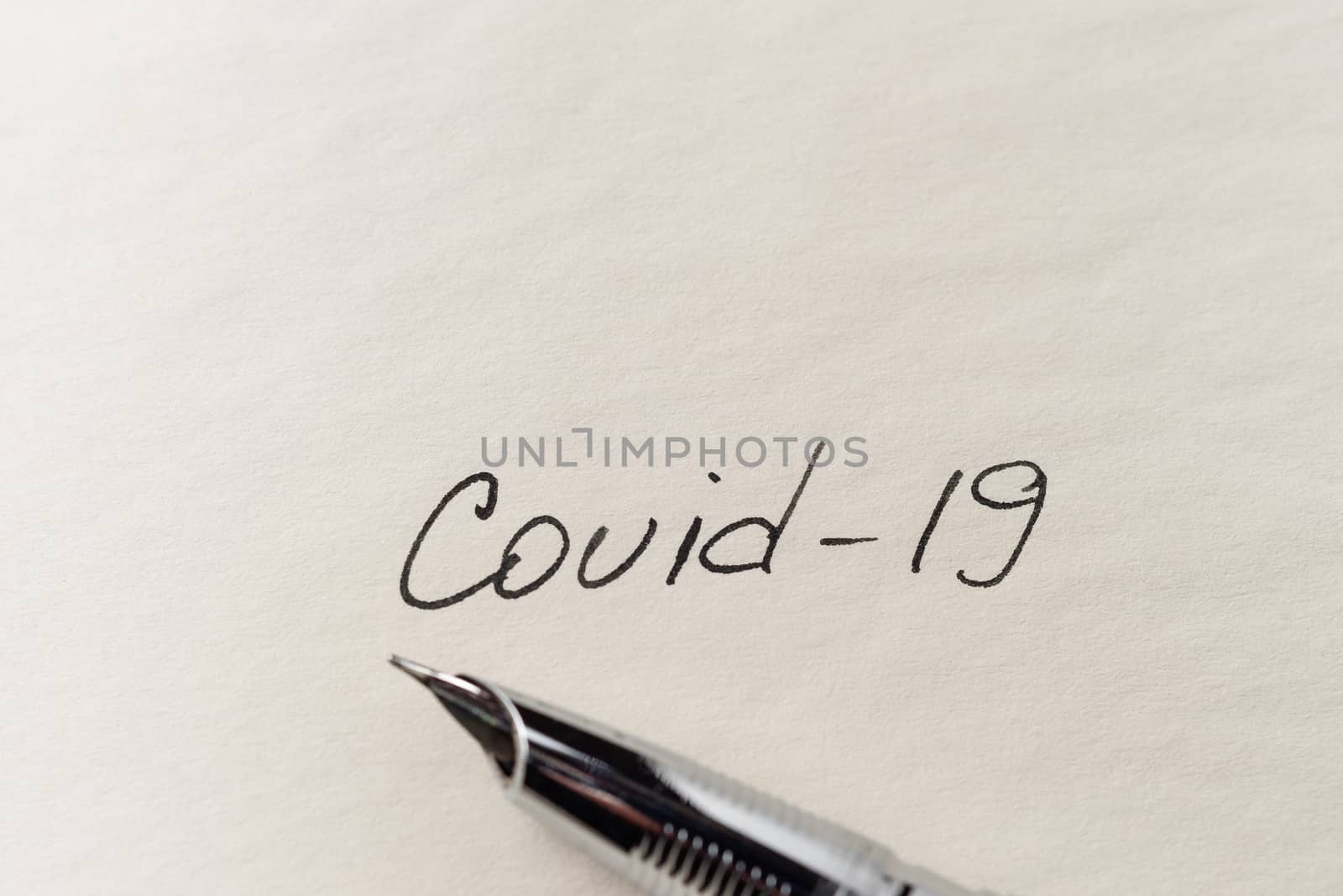 Covid-19 inscription on a blank empty sheet of paper in a notebook. Nearby lies a fountain pen. A lot of space for inscriptions and copyspace. The virus is dangerous. Blank for inscriptions. Template for article or cover.