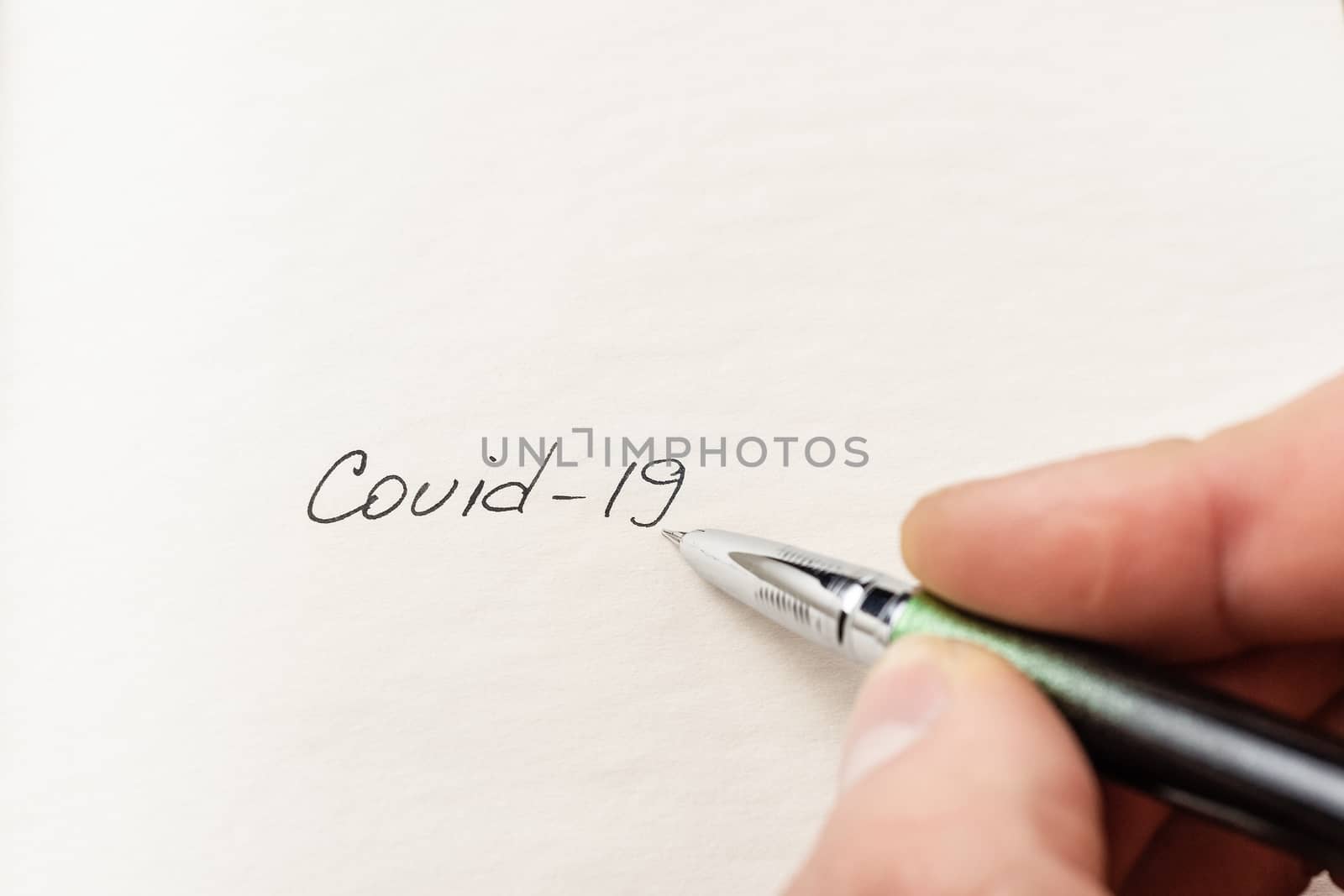 The hand writing Covid-19 on empty sheet of paper. Covid-19 insc by alexsdriver