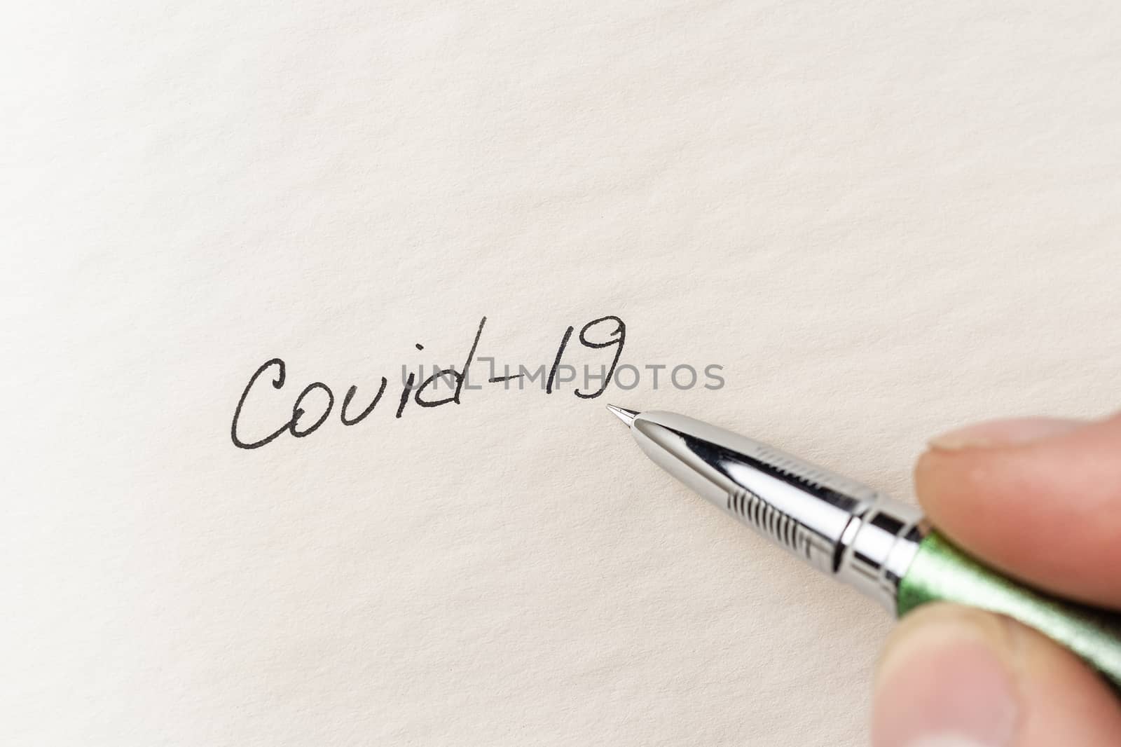 The hand writing Covid-19 on empty sheet of paper. Covid-19 insc by alexsdriver