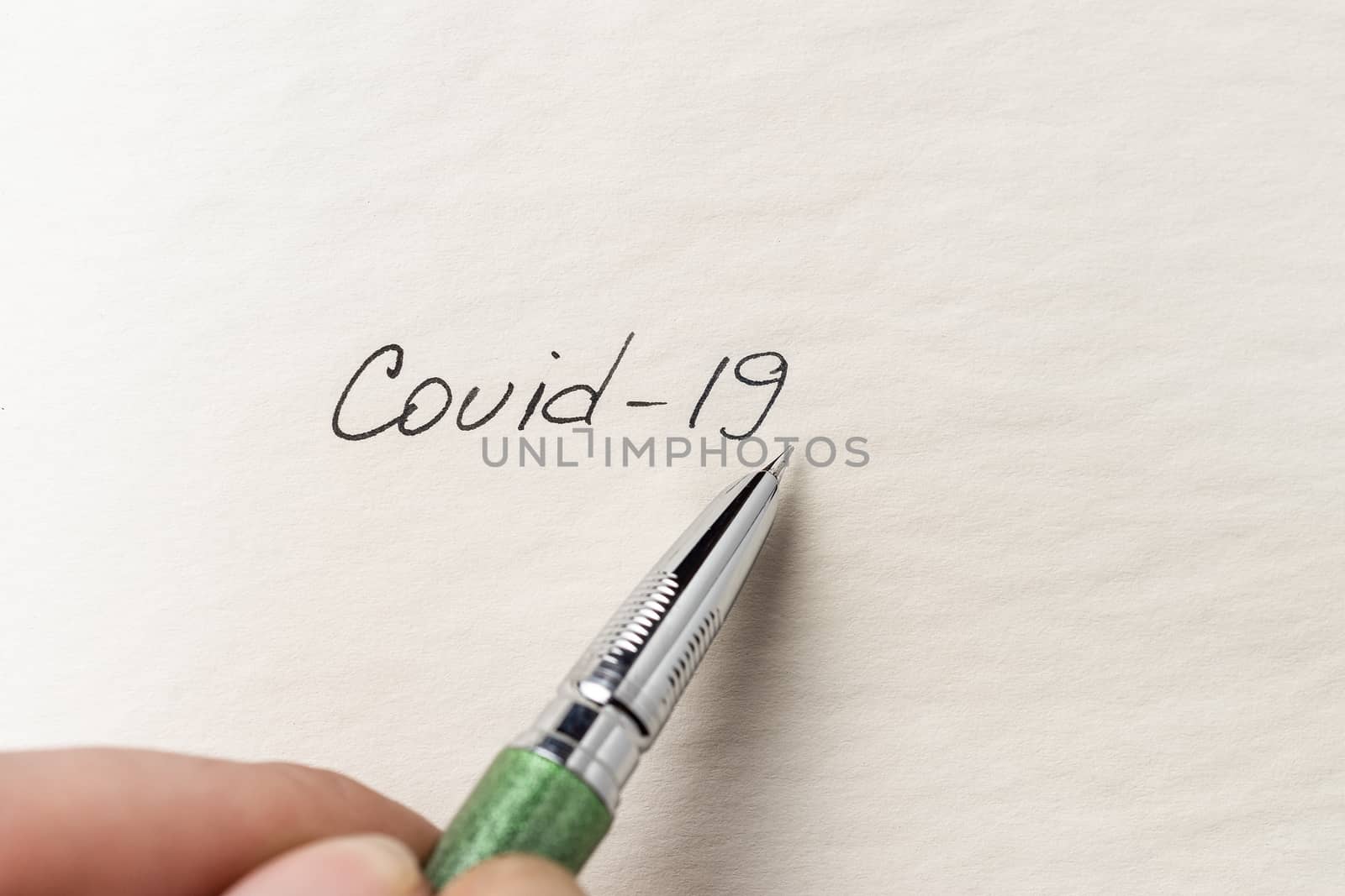 The hand writing Covid-19 on empty sheet of paper. Covid-19 insc by alexsdriver