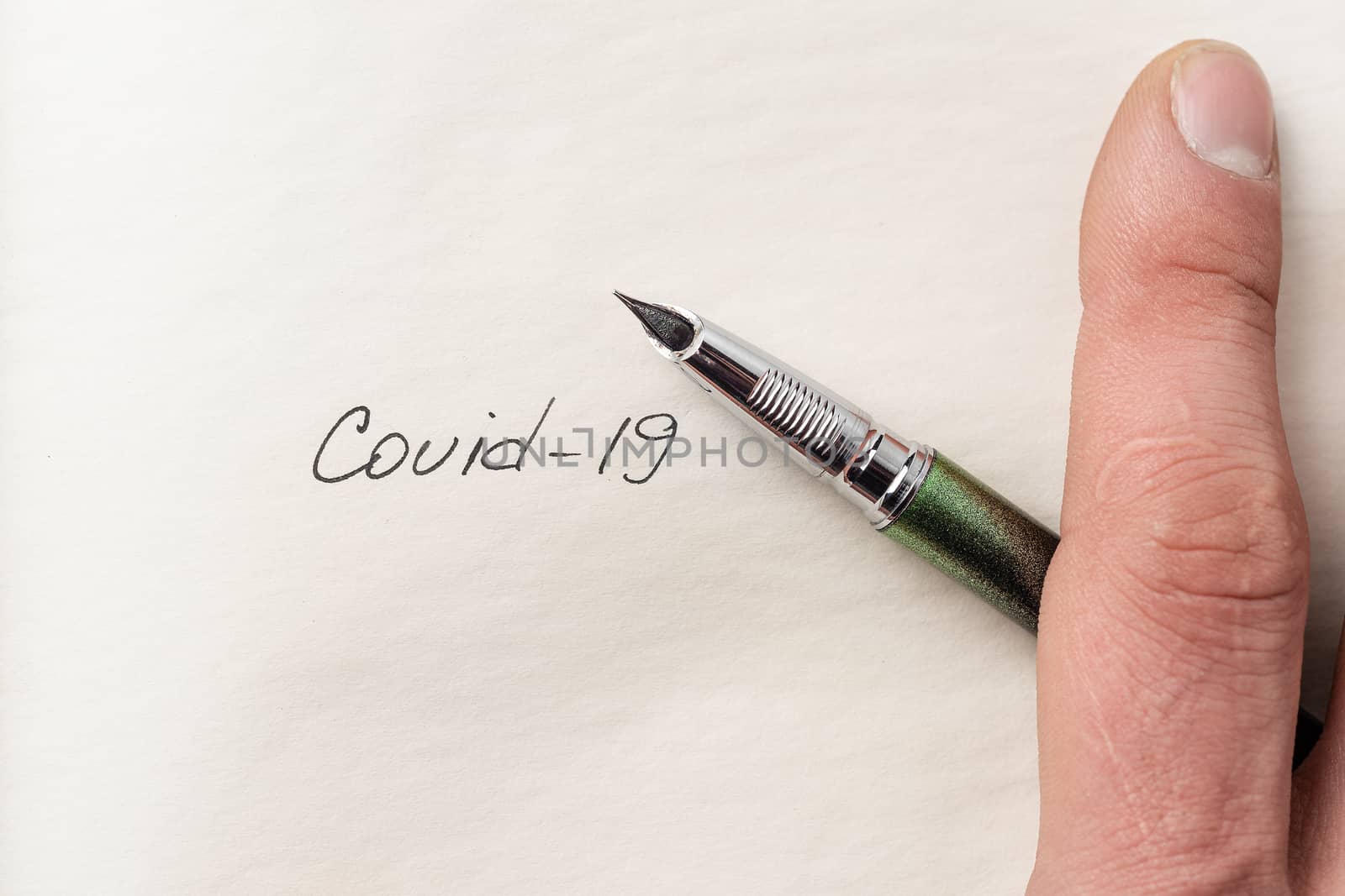 The hand writing Covid-19 on empty sheet of paper. Covid-19 insc by alexsdriver