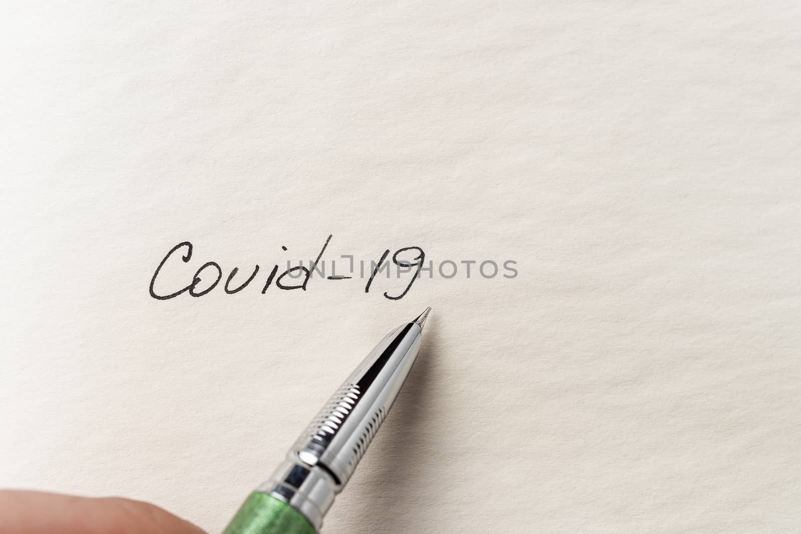 The hand writing Covid-19 on empty sheet of paper. Covid-19 insc by alexsdriver