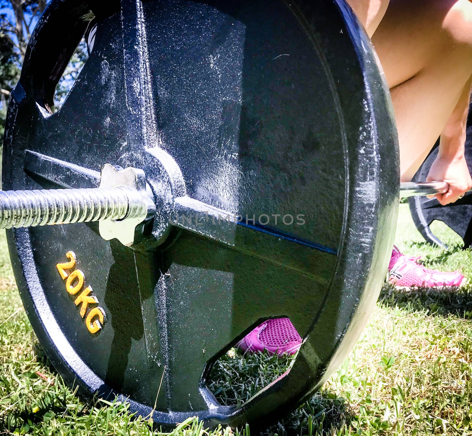 A female deadlifting a 45kg barbell on grass