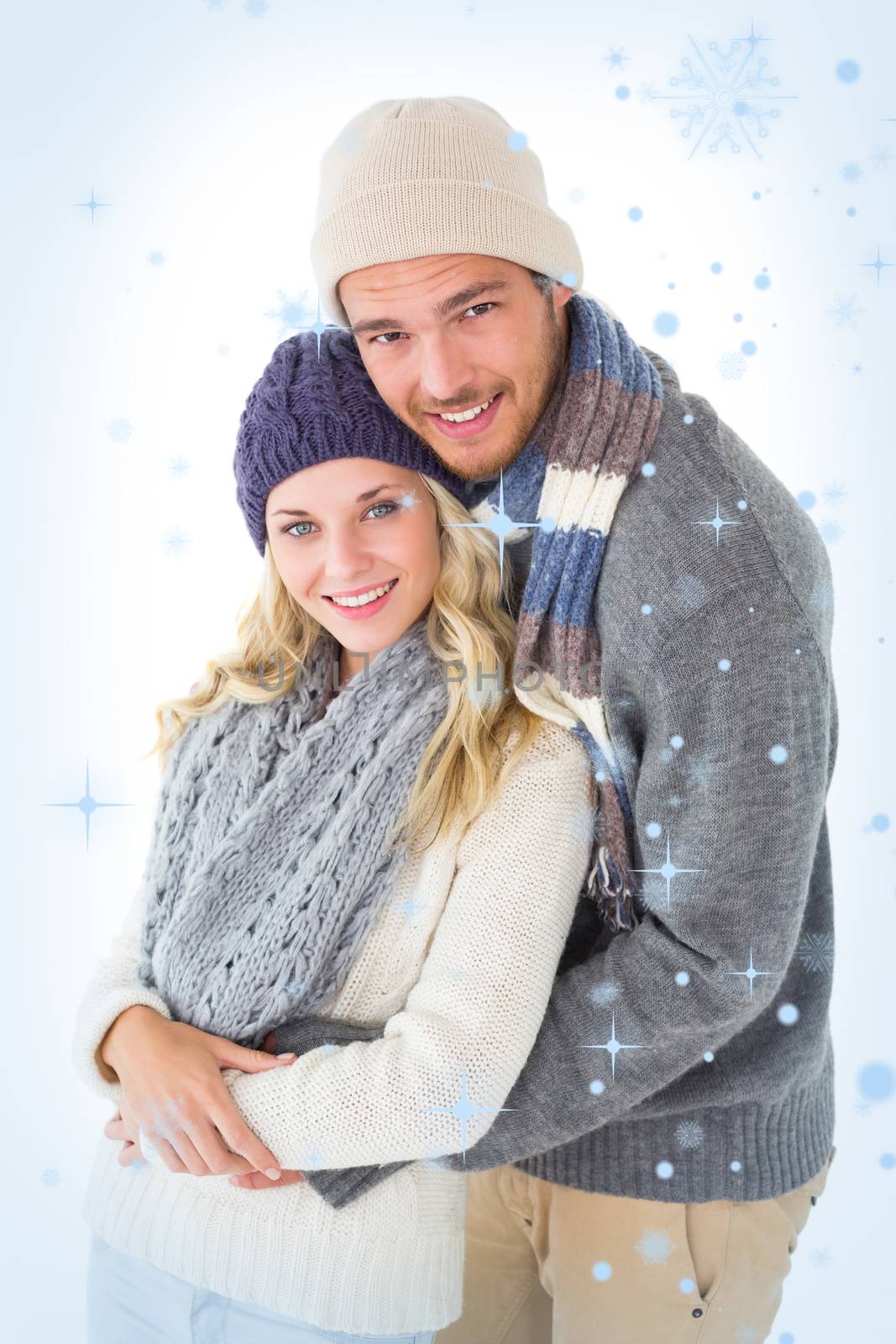 Attractive couple in winter fashion hugging against snow falling