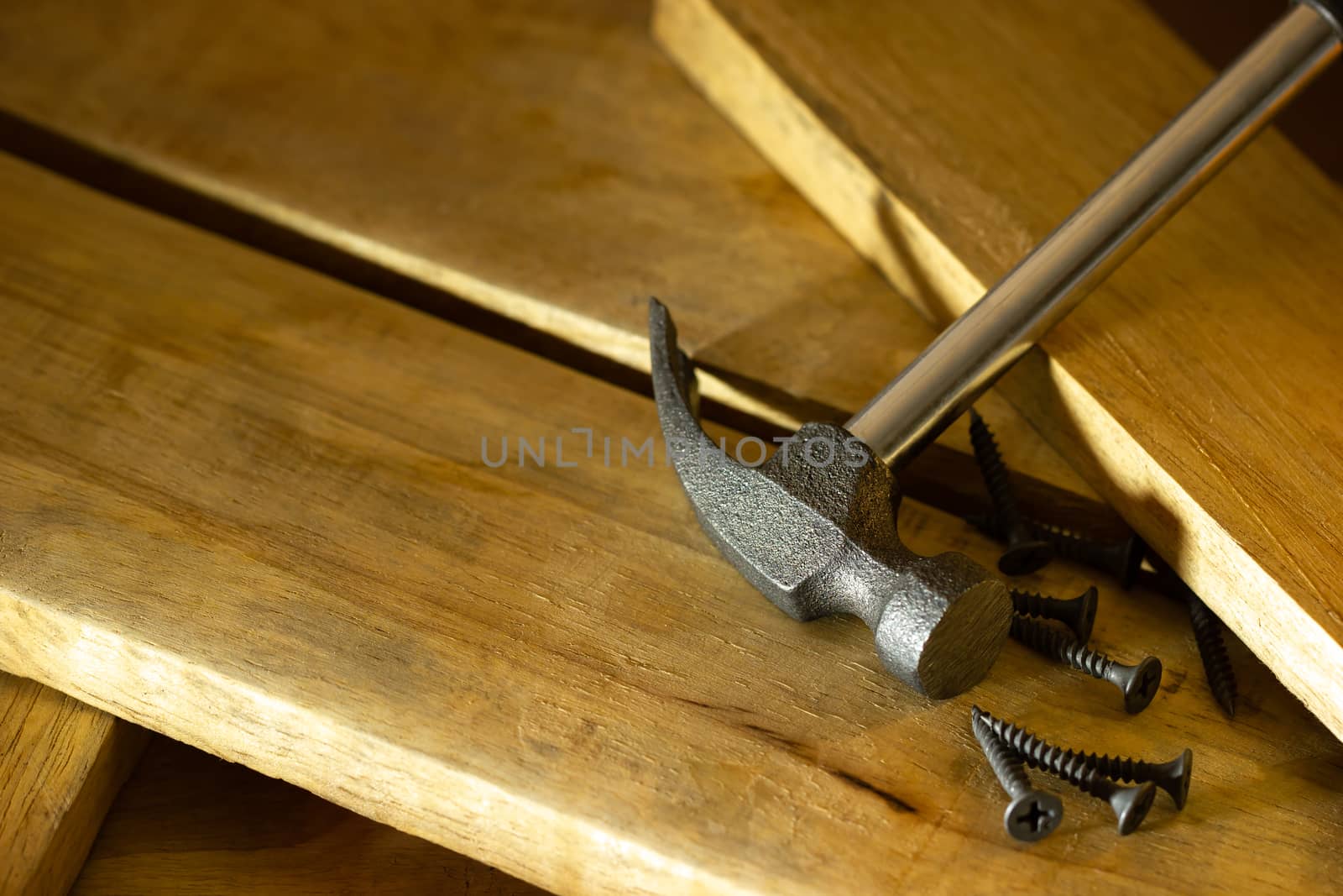 Hammer and screw on lumber in lighting and shadow of the sunshine in morning. The concept of woodcraft or carpentry.