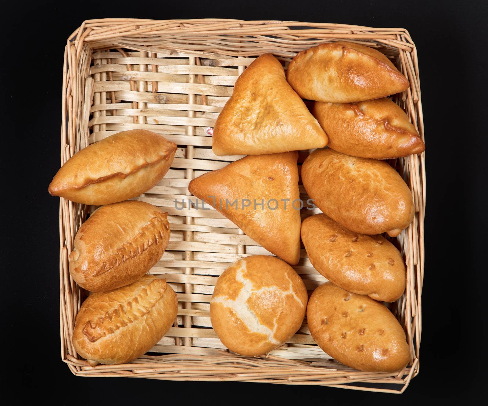 Pies with meat in the wicker basket on a black background