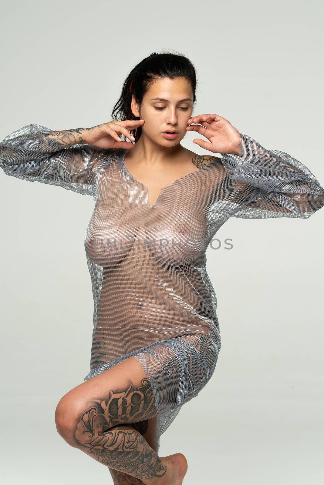 young beautiful girl posing in a transparent dress in the studio