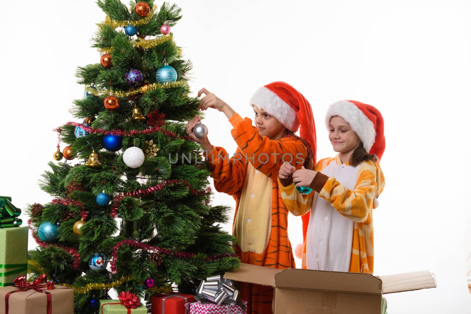 Two girls decorate a Christmas tree isolated on white background