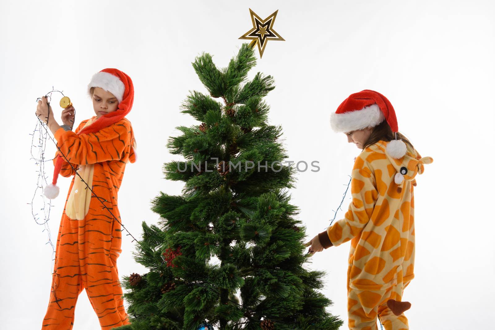 Girls remove the luminous garland from the Christmas tree
