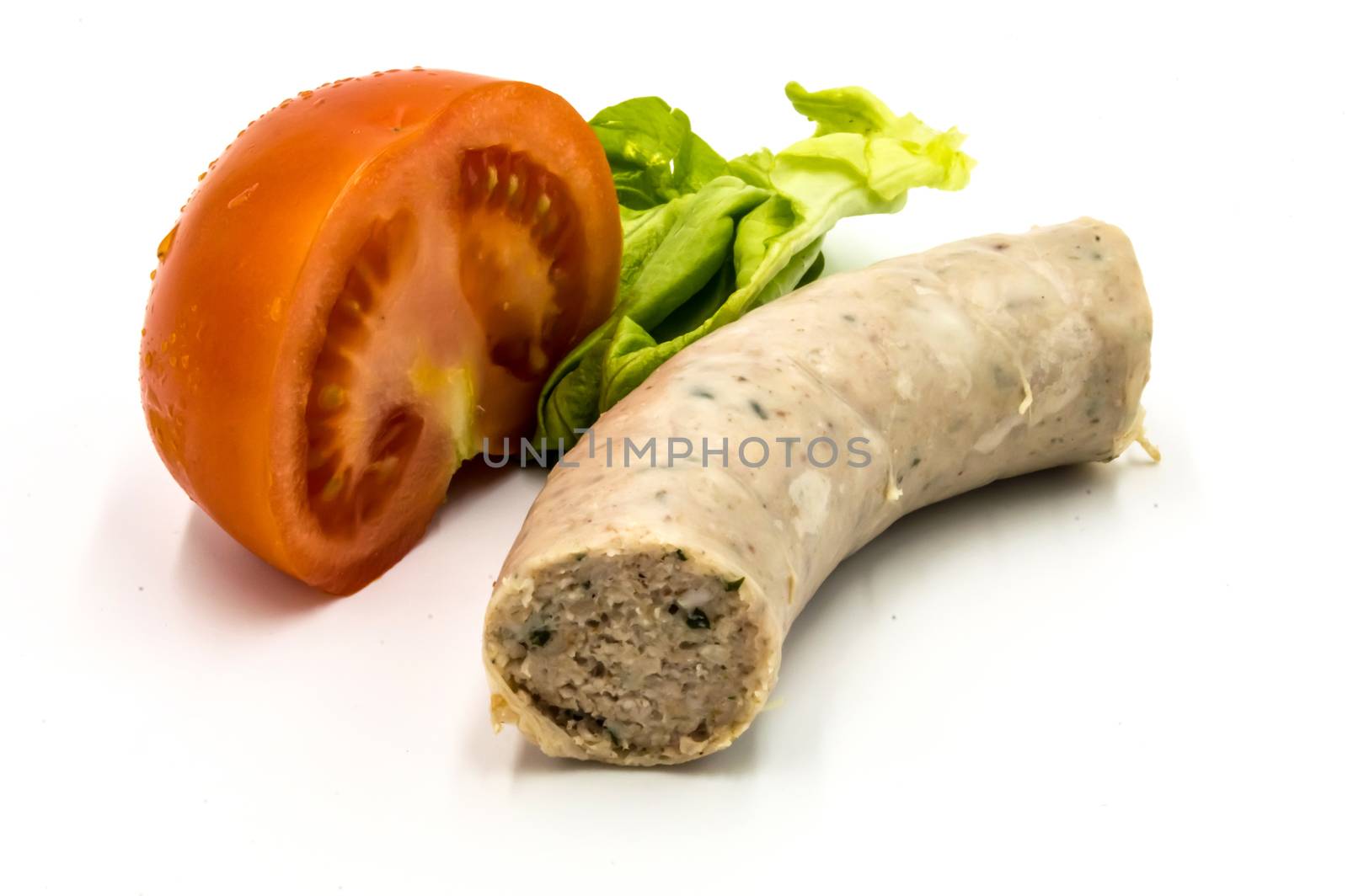 Piece of white sausage on a white background with half a tomato and a salad leaf