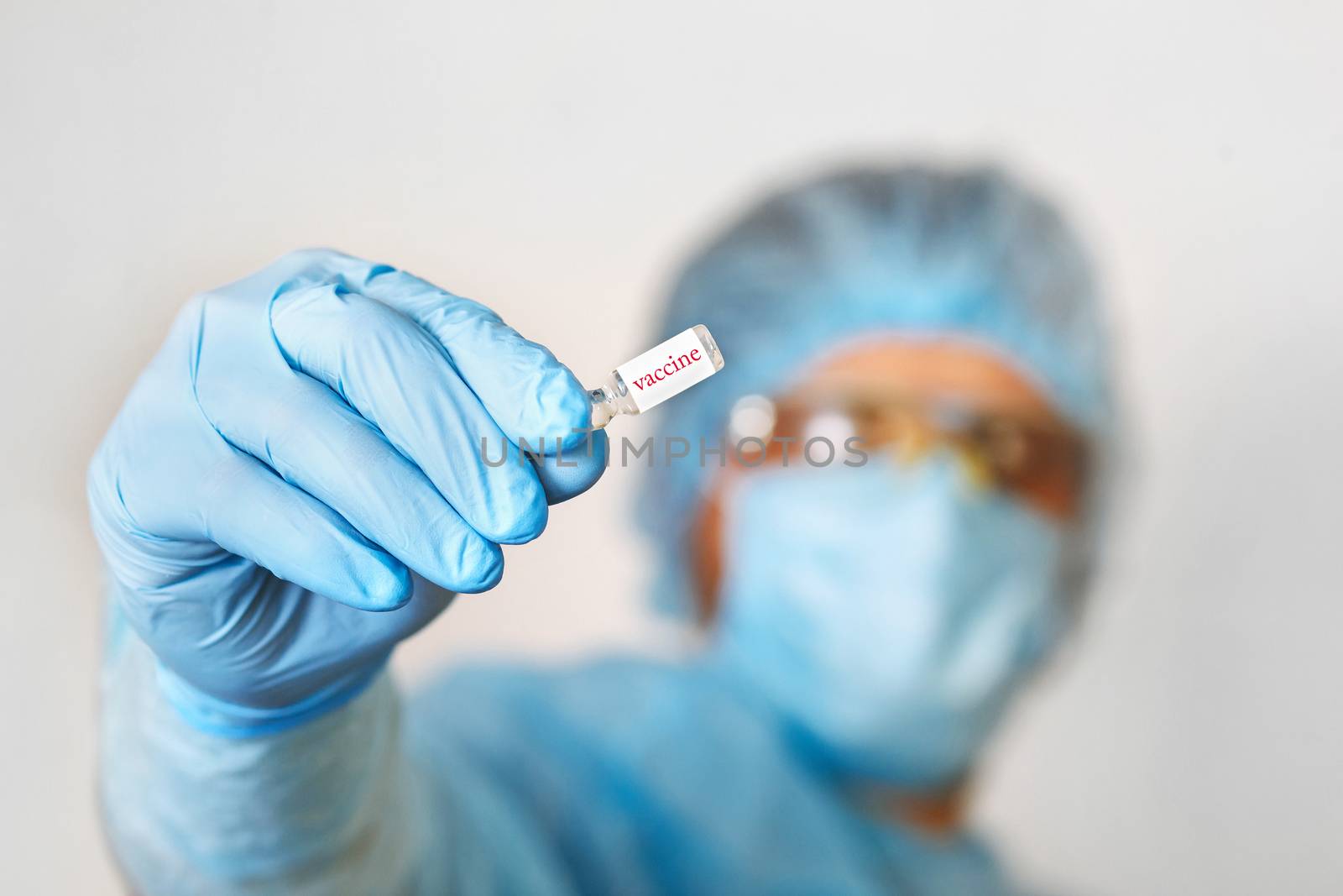 Close up of doctor hand holding vaccine. Medical equipment. A doctor wearing personal protective equipment including mask, goggle, and suit to protect COVID 19 coronavirus infection.