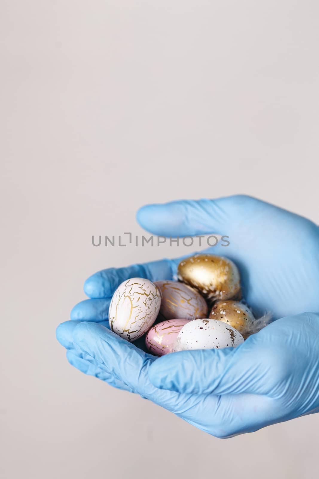 Hands in medical gloves holding modern painted easter eggs. Selective focus. Toned picture. Isolated.