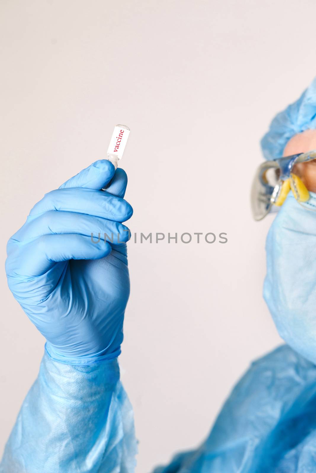 Close up of doctor hand holding vaccine. Medical equipment. A doctor wearing personal protective equipment including mask, goggle, and suit to protect COVID 19 coronavirus infection.