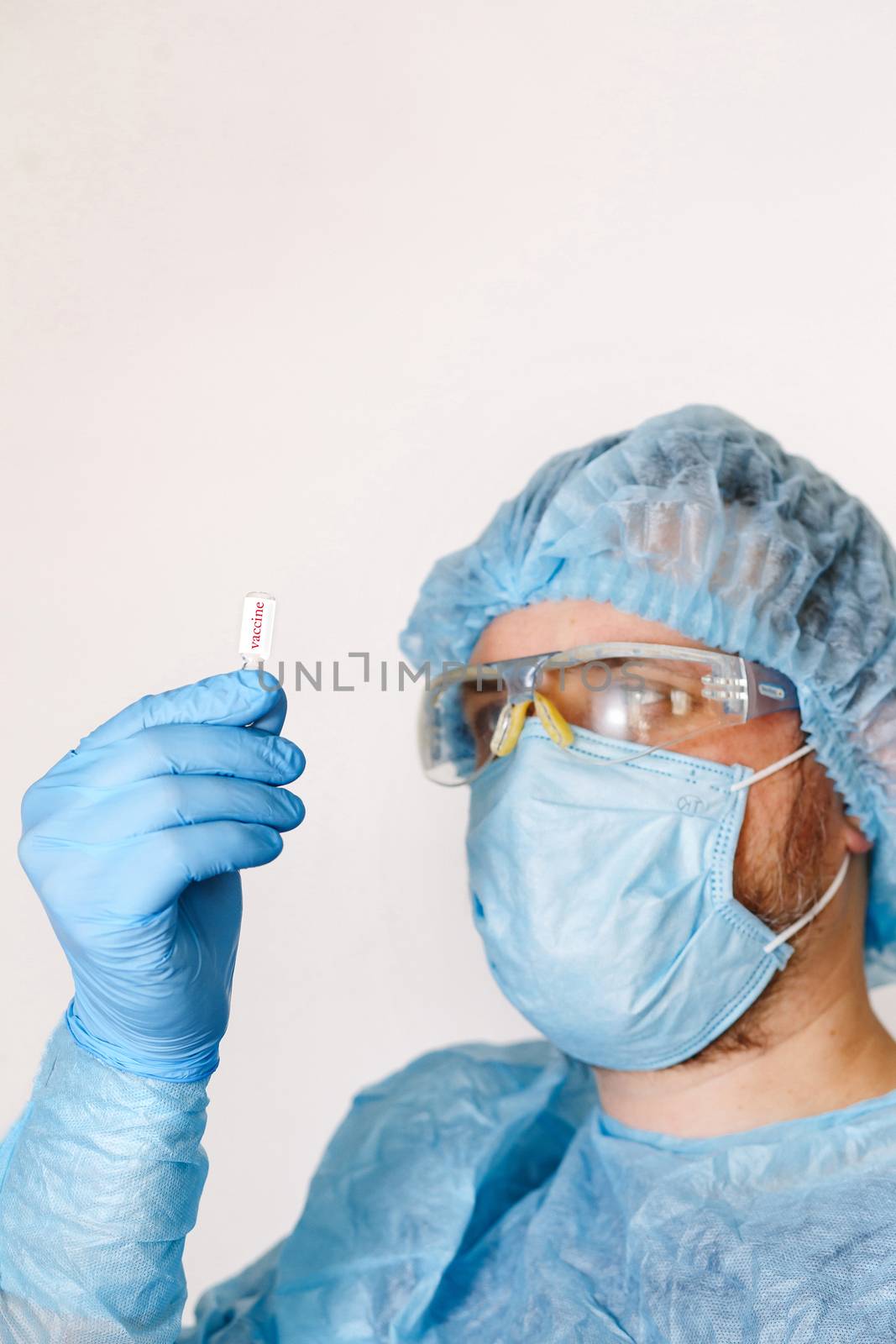 Close up of doctor hand holding vaccine. Medical equipment. A doctor wearing personal protective equipment including mask, goggle, and suit to protect COVID 19 coronavirus infection.