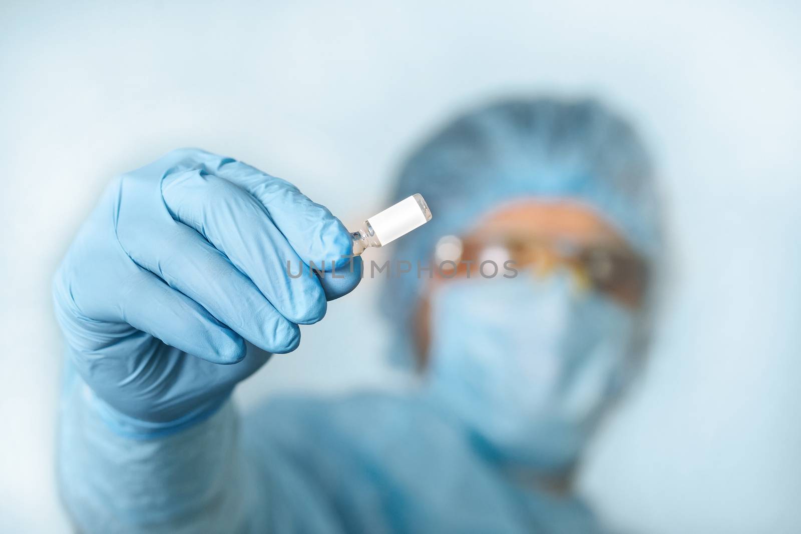 Close up of doctor hand holding vaccine. Medical equipment. A doctor wearing personal protective equipment including mask, goggle, and suit to protect COVID 19 coronavirus infection.
