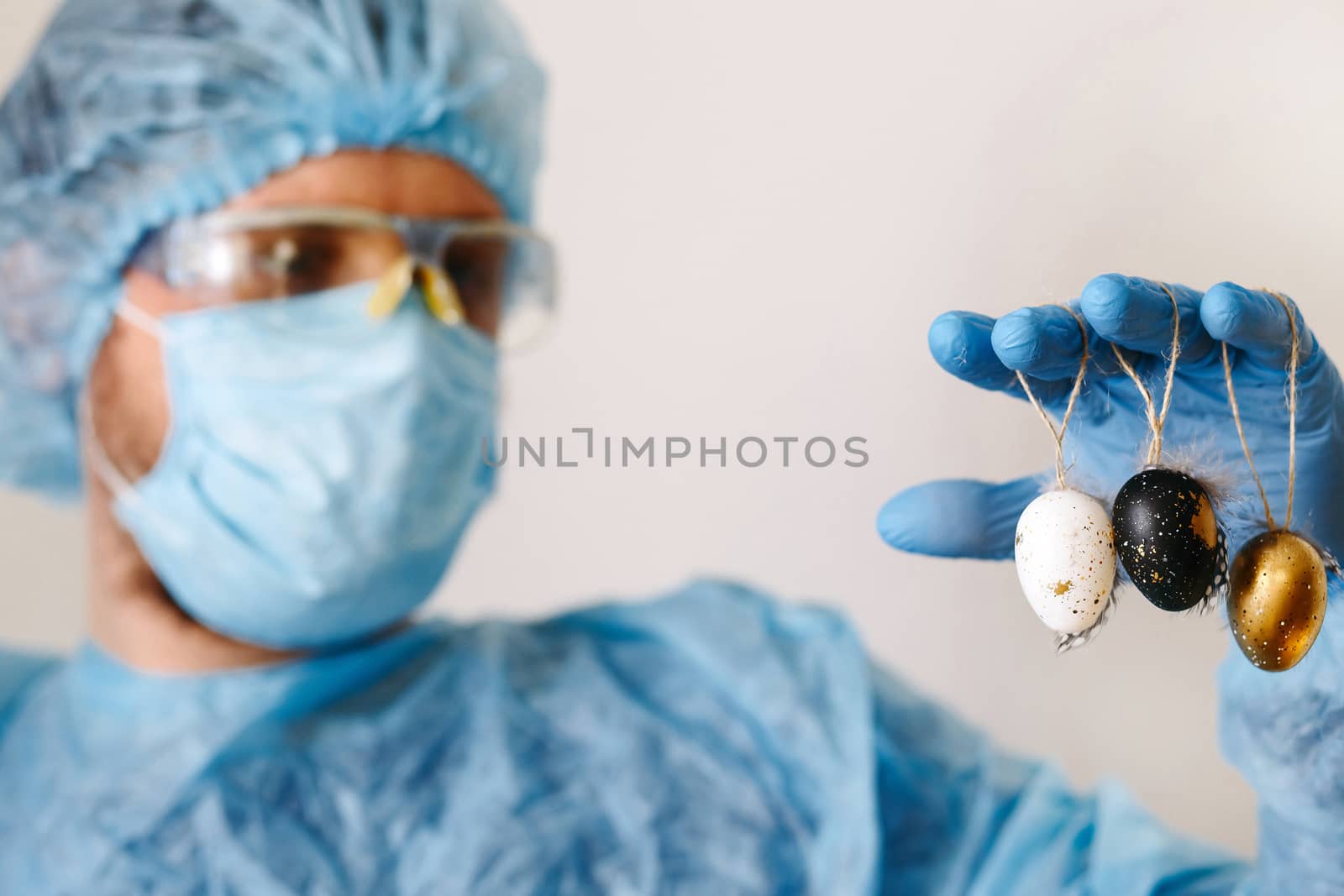 Hands in medical gloves holding modern painted easter eggs. Selective focus. Toned picture.