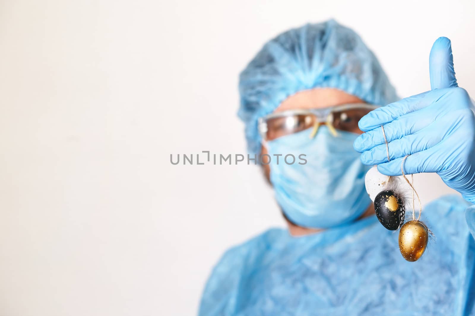 Hands in medical gloves holding modern painted easter eggs. Selective focus. Toned picture.