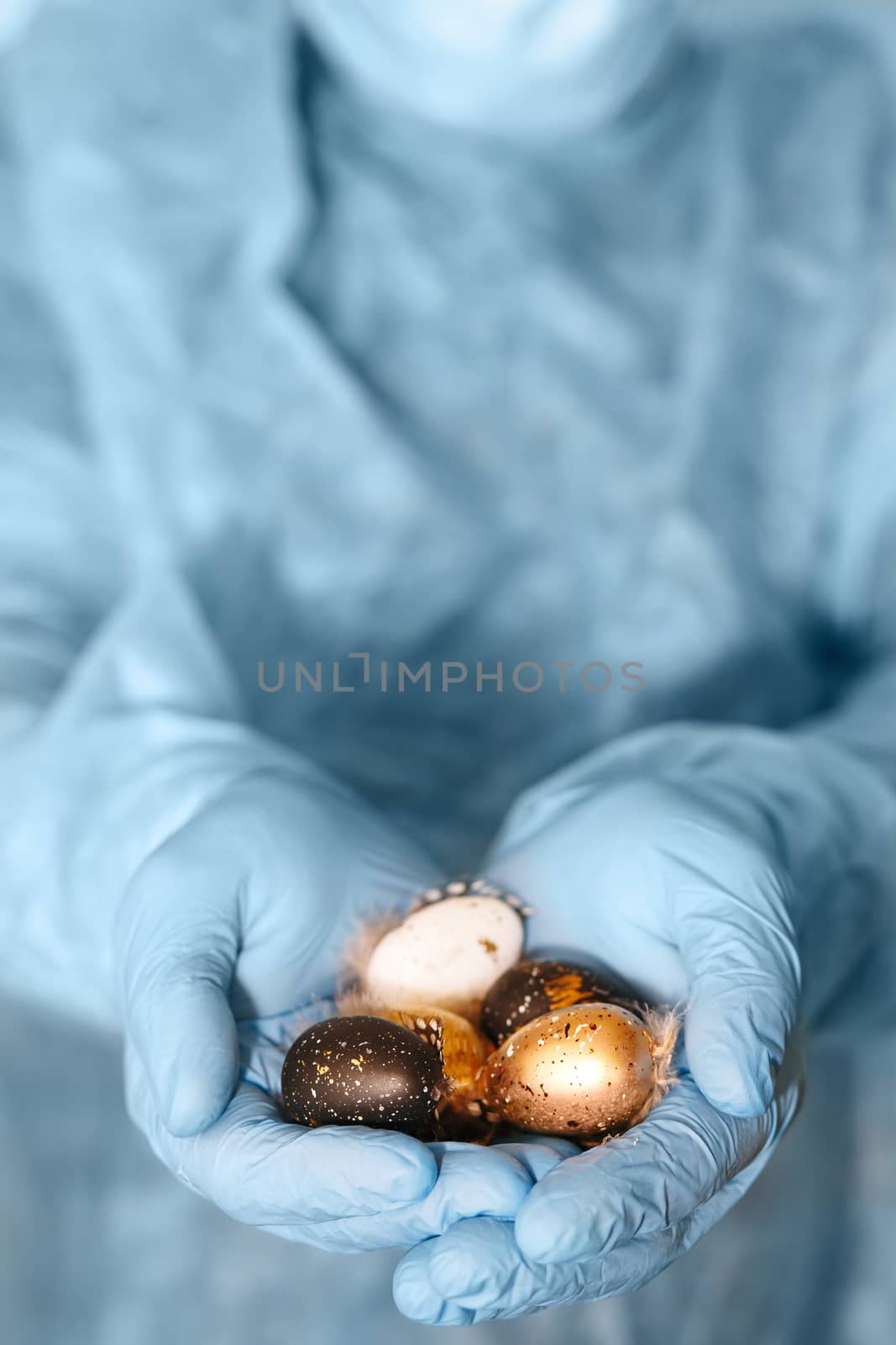 Hands in medical gloves holding modern painted easter eggs. Selective focus. Toned picture.