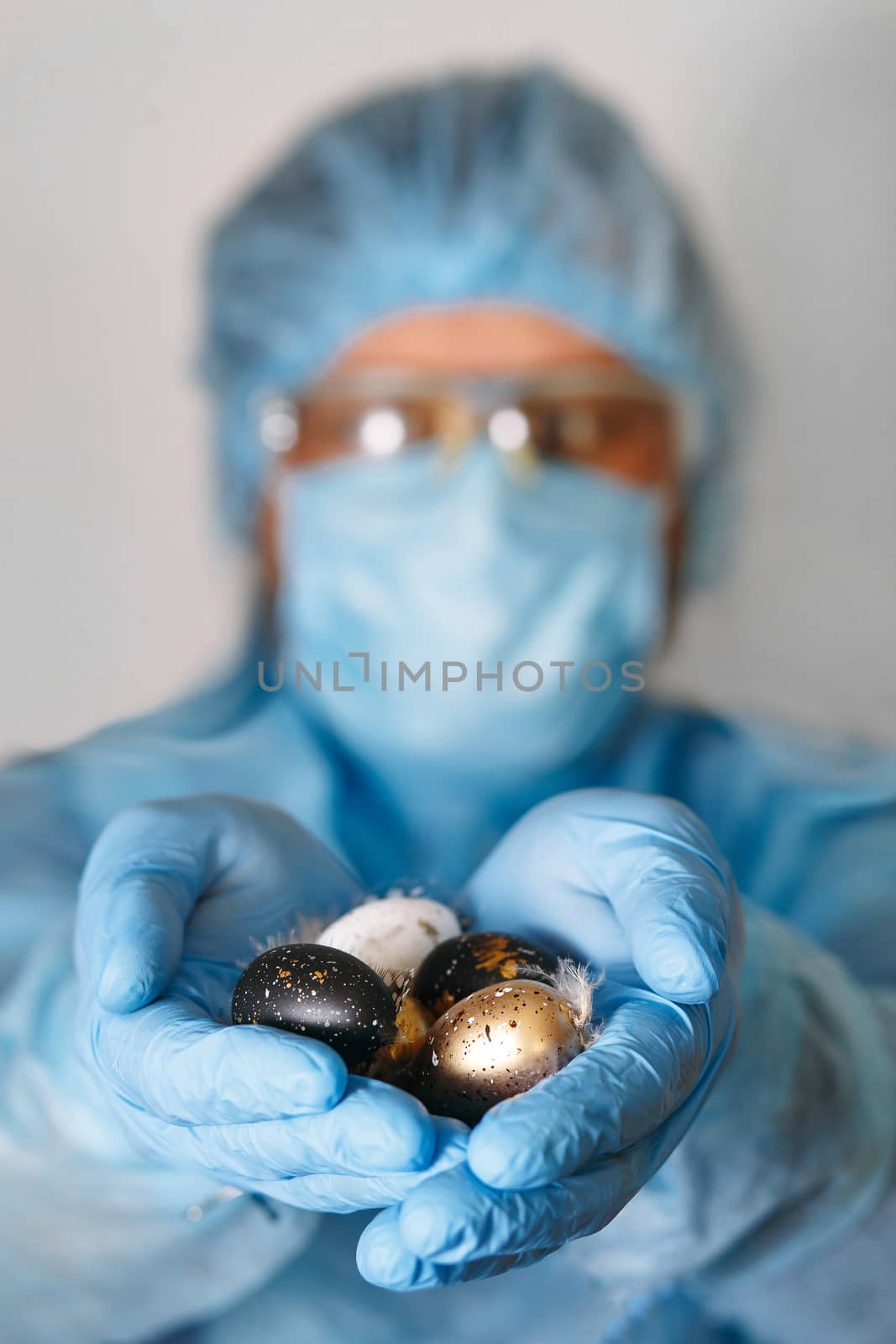Hands in medical gloves holding modern painted easter eggs. Selective focus. Toned picture.