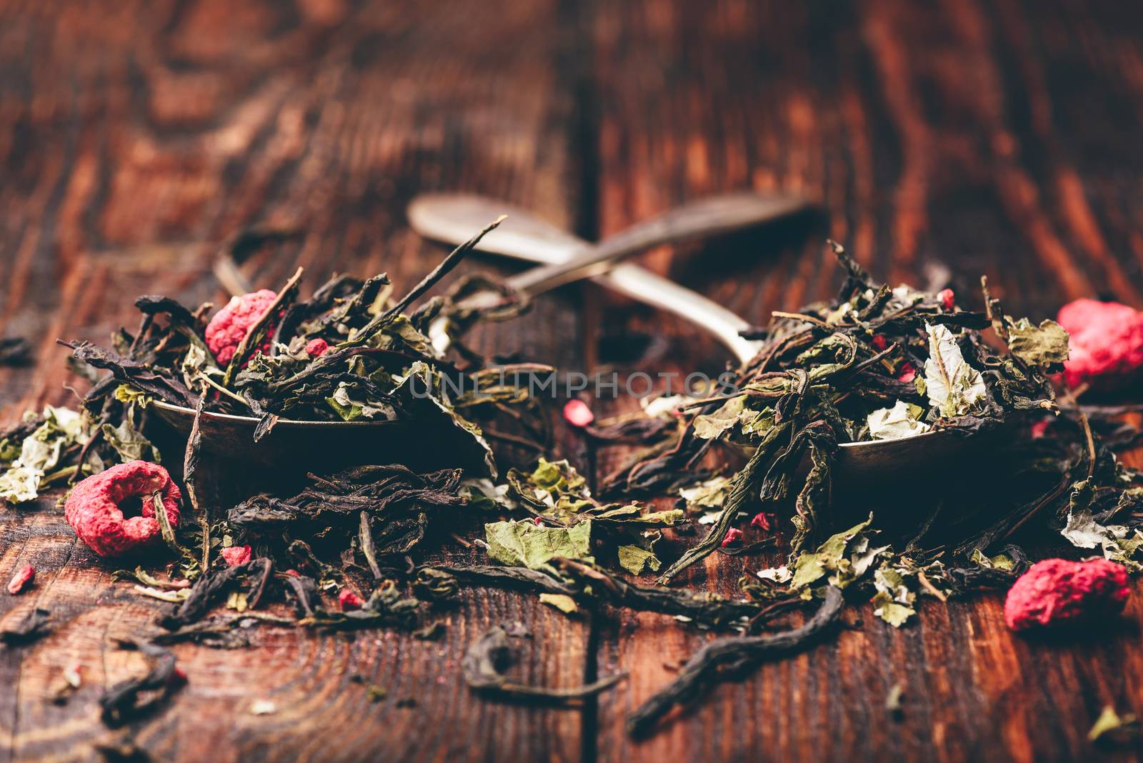 Two spoonfuls of raspberry herbal tea over wooden surface