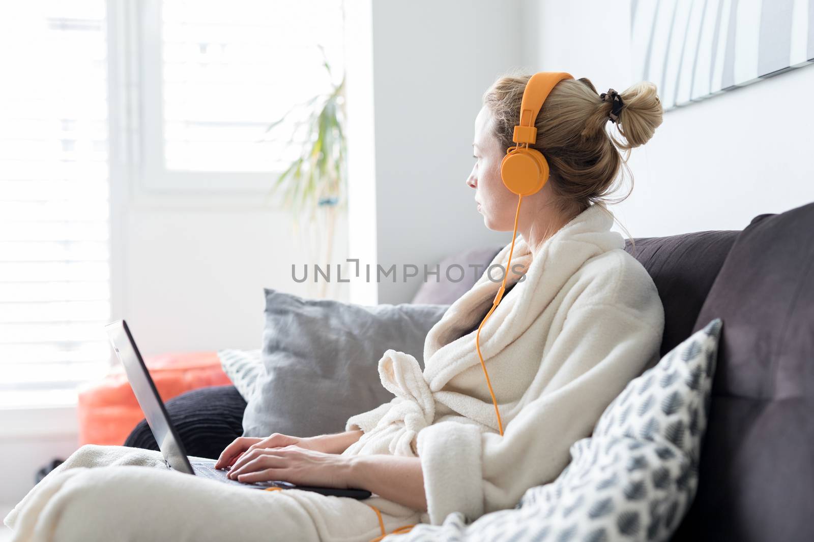 Stay at home and social distancing. Woman in her casual home bathrobe working remotly from her living room. Video chatting using social media with friend, family, business clients or partners.