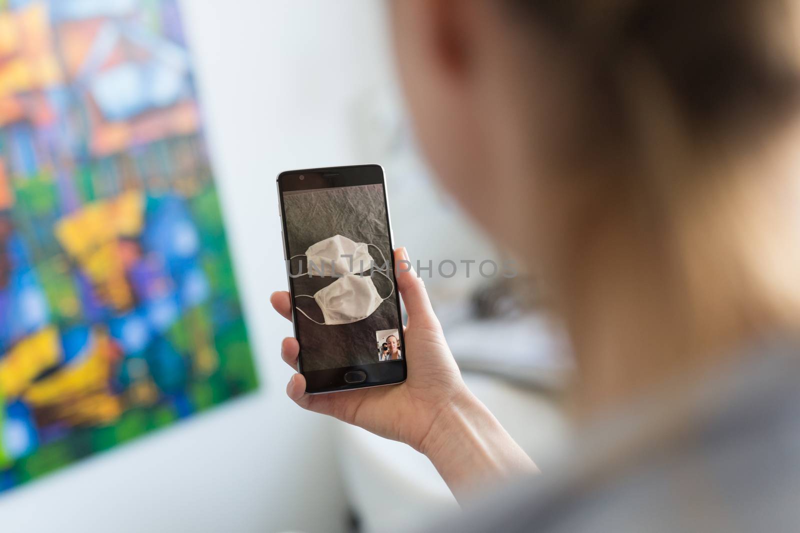 Stay at home, social distancing lifestyle. Woman at home using social media on phone to learn about the use of masks and preventative measures during corona virus pandemic. by kasto