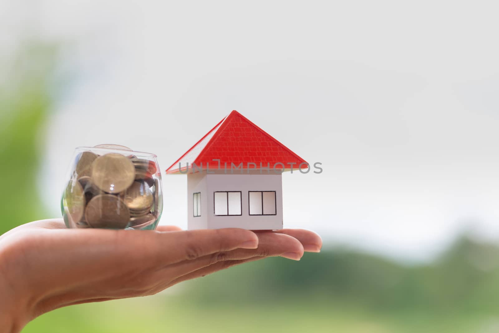 Orange roof house in investor's hand Placed close to the medallion, increasing the number of coins. Real estate investment concept, saving and buying houses, mortgage and bank loans.