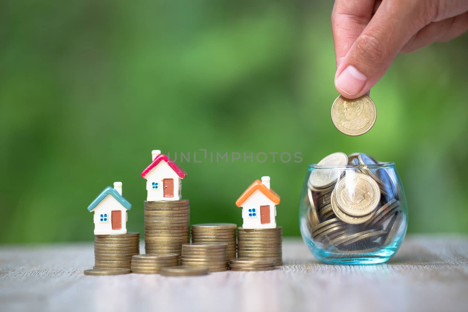 House on a pile of coins. A coin in a glass bottle The hand is about to coin. The concept of business growth Saving money real estate accounting Investment risk.