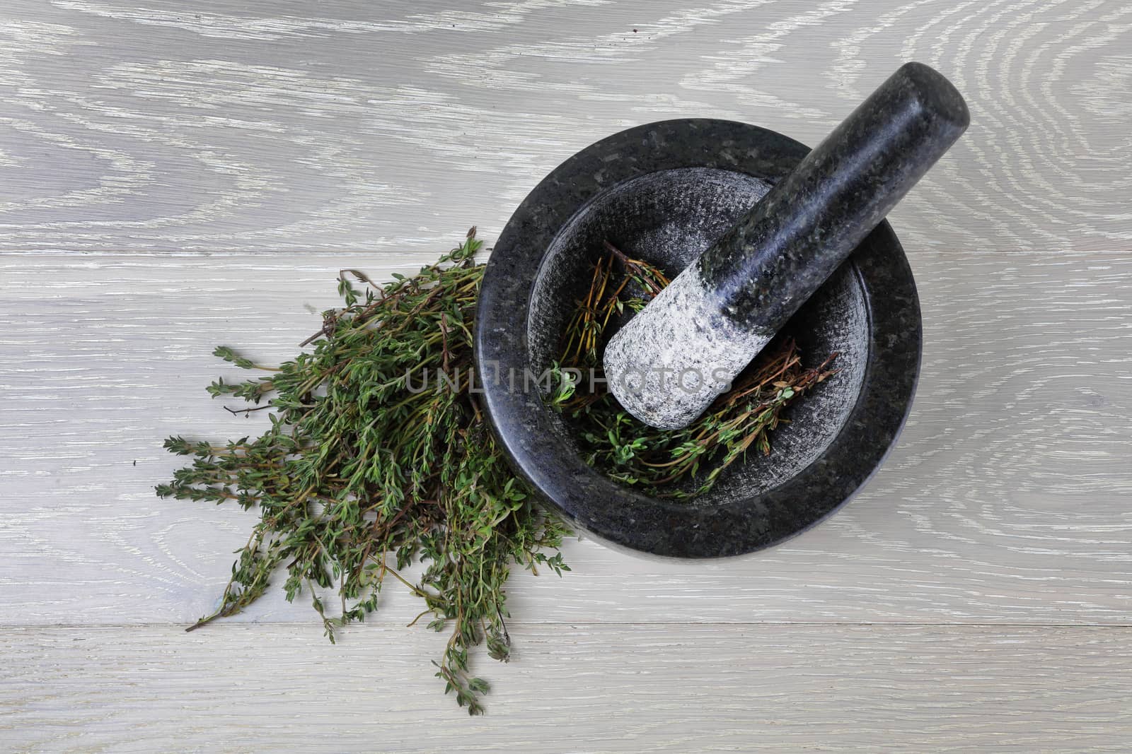 Top view of thyme on wood surface and mortar and pestle by VivacityImages