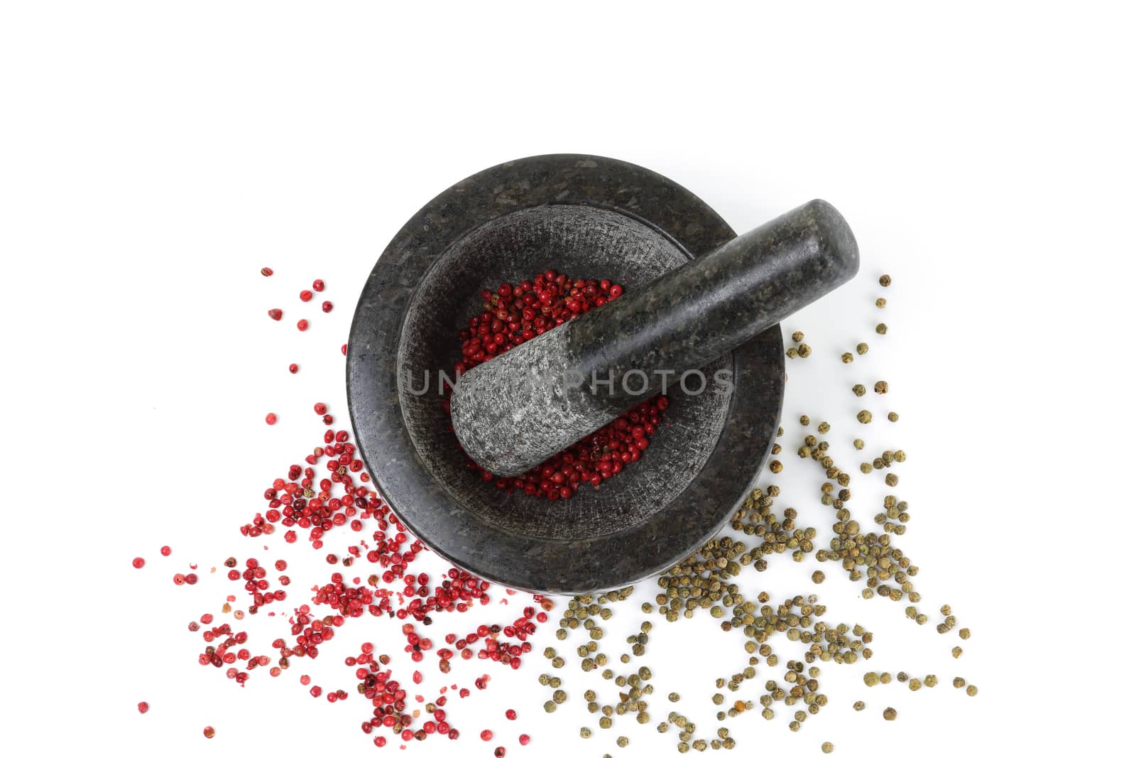 A top view of pink and green peppercorns with mortar and pestle isolated on white