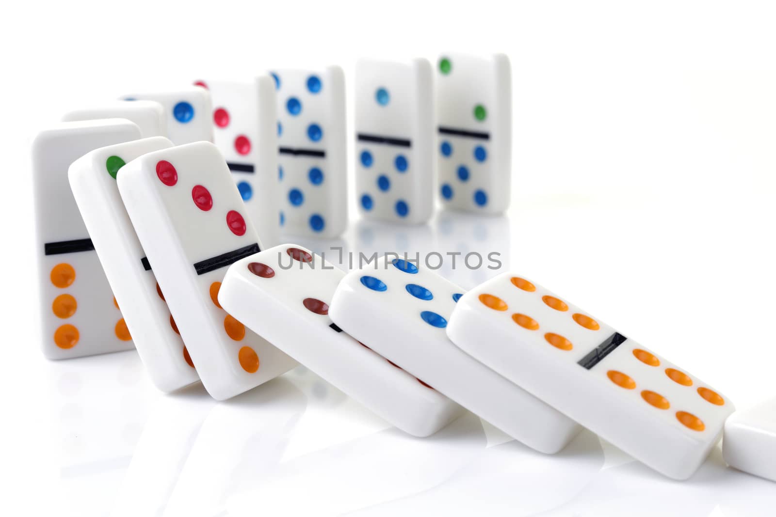 Falling colorful dominoes on a white surface by VivacityImages