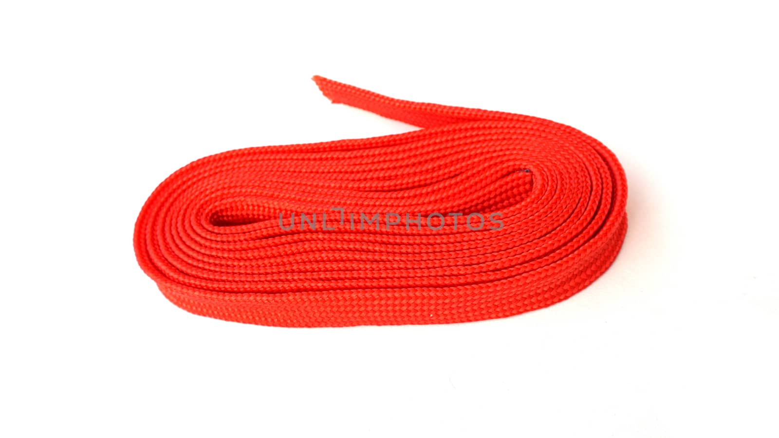 Red rope on white background. Fabric rope in red color folded in a coil.