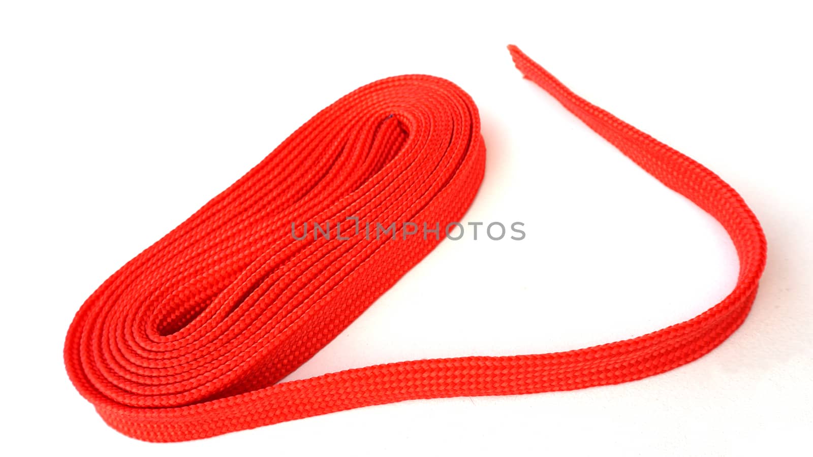 Red rope on white background. Fabric rope in red color folded in a coil.