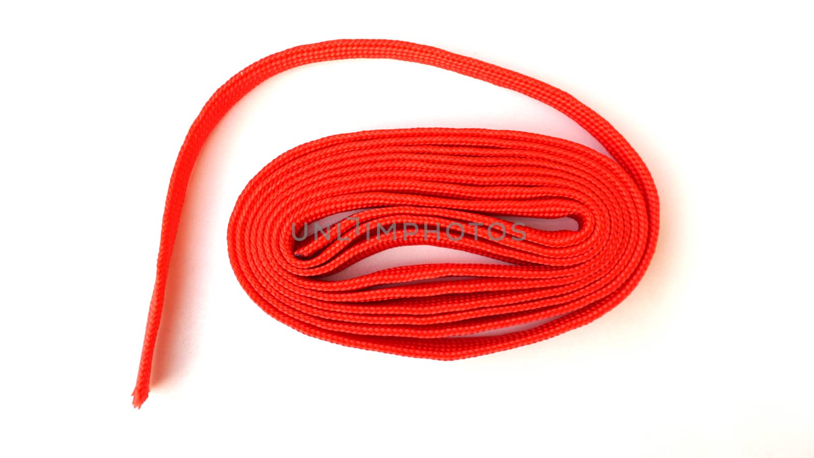 Red rope on white background. Fabric rope in red color folded in a coil.