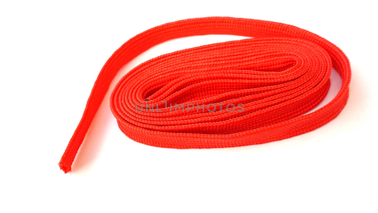 Red rope on white background. Fabric rope in red color folded in a coil.
