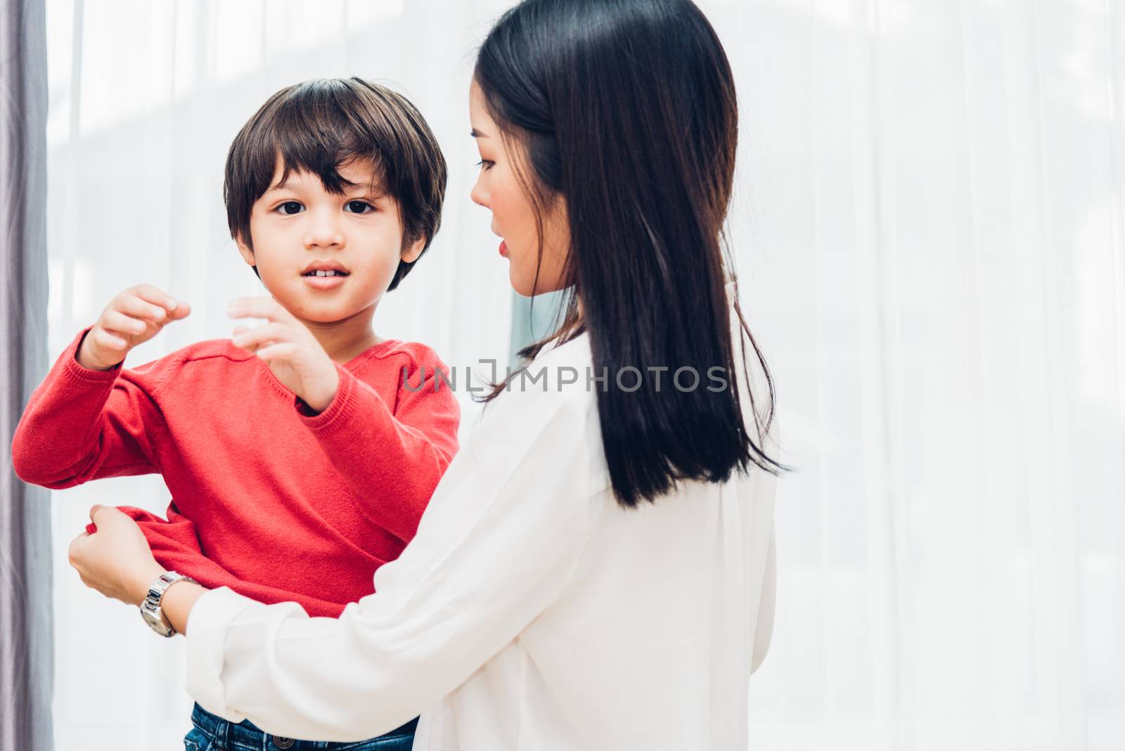 Asian happy beautiful mother getting dressed clothes on her kids by Sorapop