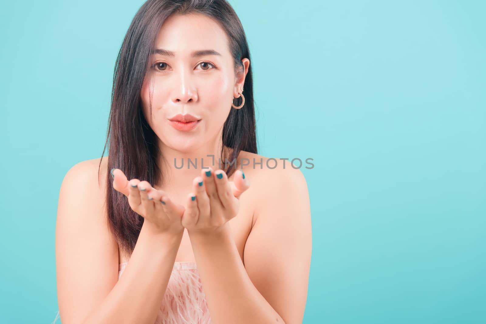 woman standing smiling blowing something on hands by Sorapop