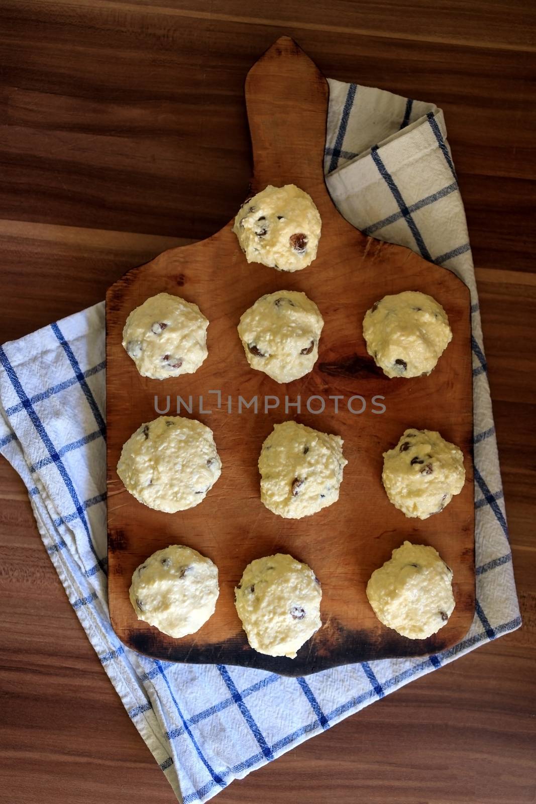 On the board prepared for frying Russian traditional home-made cottage cheese pancakes with raisins - cheesecakes on a wooden table by Tanacha