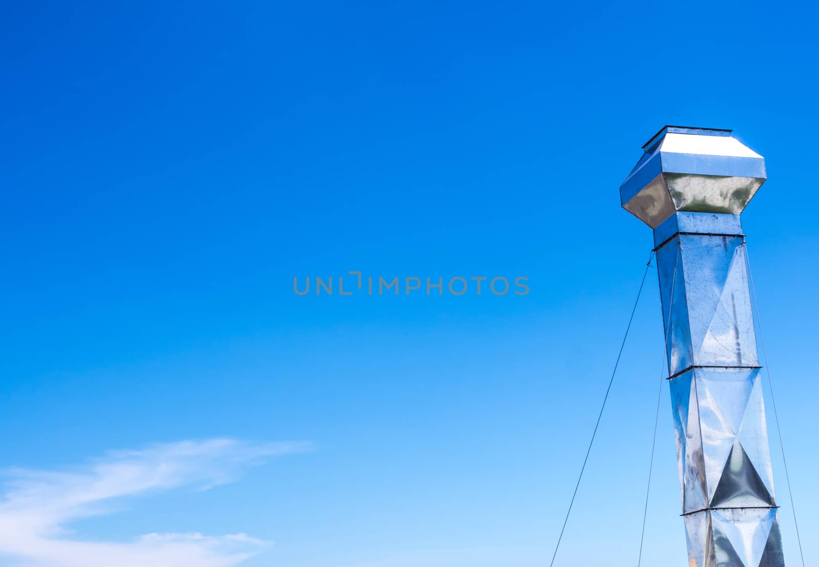 Shiny steel smokestack and cloud in blue sky