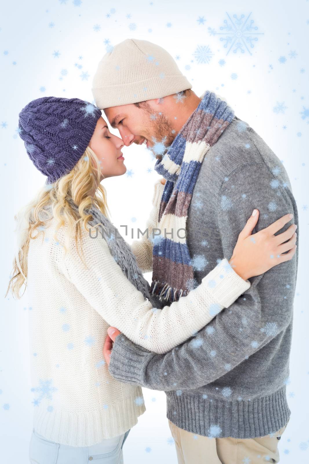 Attractive couple in winter fashion hugging against snow falling