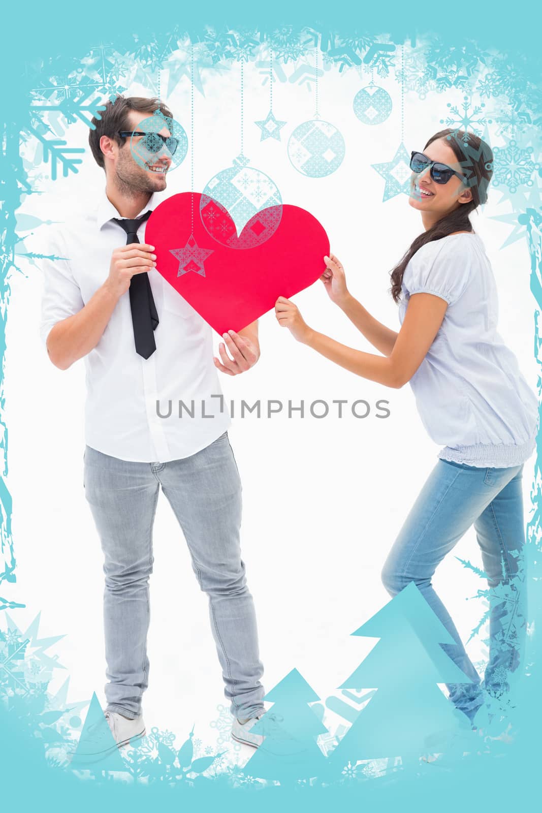 Hipster couple smiling at camera holding a heart against christmas frame