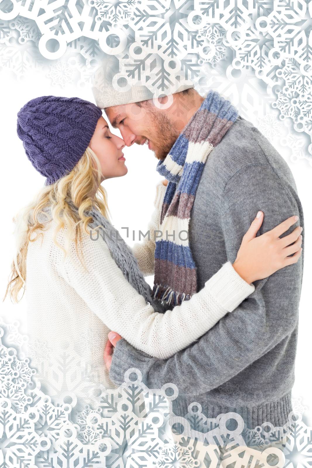 Attractive couple in winter fashion hugging against snowflakes on silver