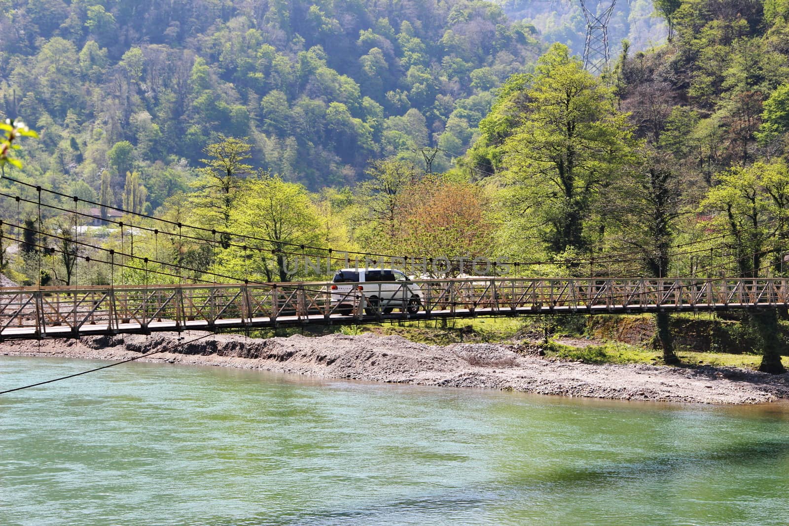 Photo of The car goes over the bridge over the river, which the villagers of Mirveti built themselves. Spring, Georgia