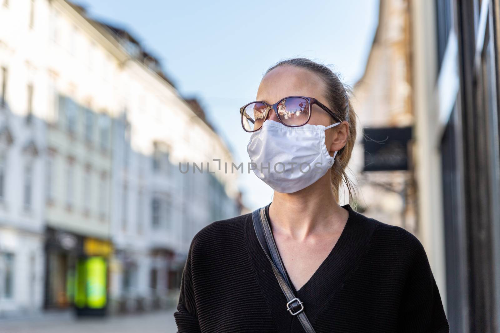 COVID-19 pandemic coronavirus. Young girl in city street wearing face mask protective for spreading of coronavirus disease 2020. Close up of young woman with medical mask on face against SARS-CoV-2.