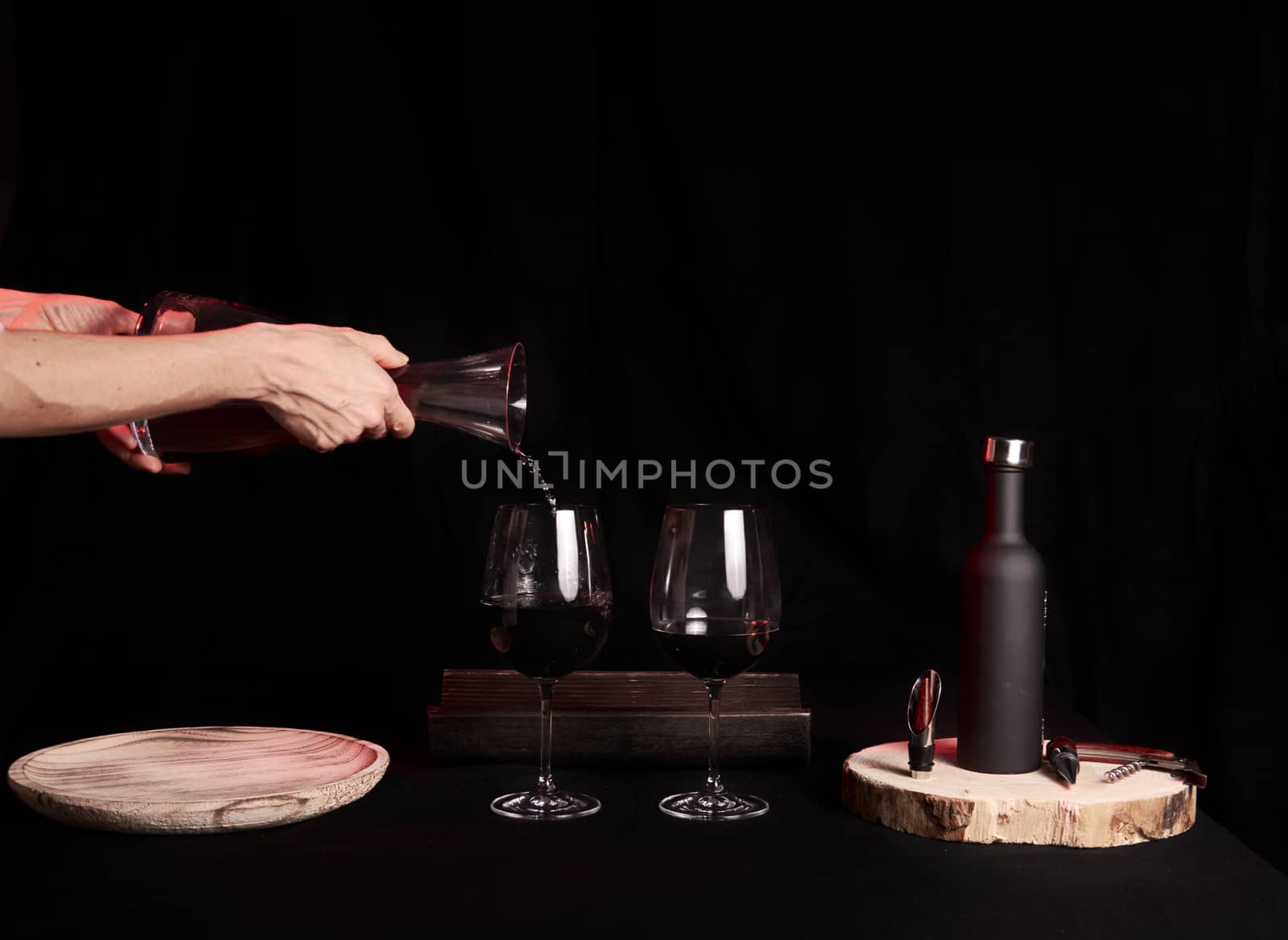 Pouring two wine glasses on black background, glass pourer wine bottle and wine utensils