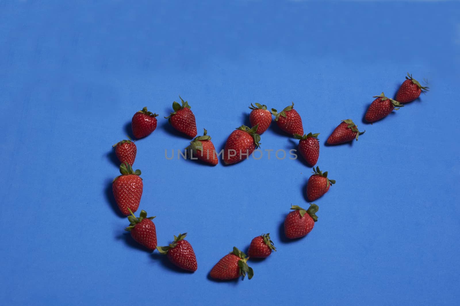 Heart made of strawberries on blue background by raul_ruiz