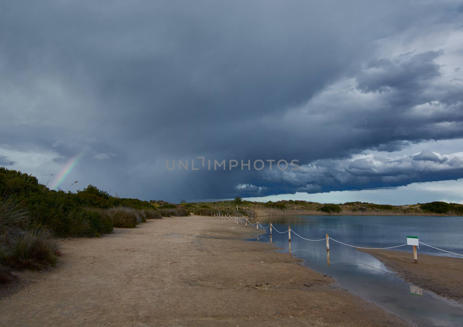 Dark clouds in sunset over the lake. Sunset colors